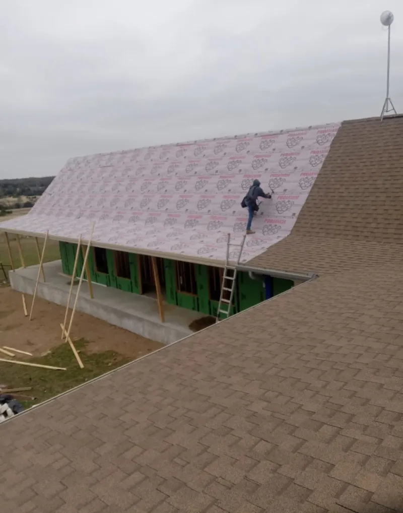 Worker preparing underlayment for a metal roof installation in Morris